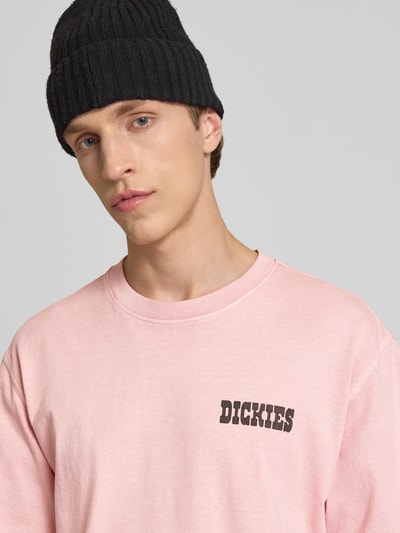 Männermodel trägt T-Shirt mit Logo und Rundhalsausschnitt von Dickies in Rosa aus reiner Baumwolle, Relaxed Fit, Nahaufnahme Oberkörper.