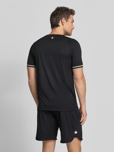 Männermodel trägt Regular Fit T-Shirt mit Label Print Modell 'TOC SERVE 2' von BOSS Green in Schwarz, Kontraststreifen, elastisch, Ganzkörperansicht Rückansicht.