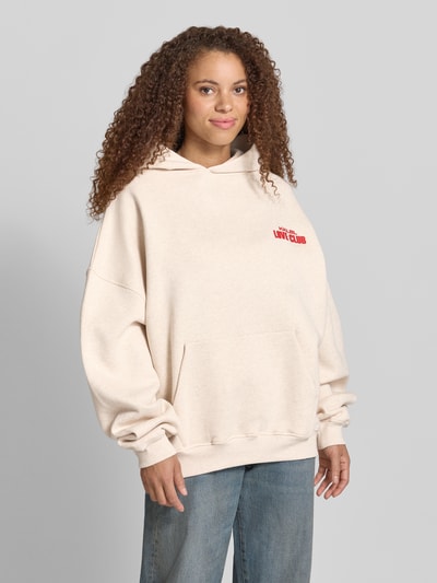 Frauenmodel trägt Hoodie mit Statement-Print Modell 'Love Club' von Karo Kauer aus Reine Baumwolle im Oversized-Fit, Kapuze, Känguru-Tasche, Ganzkörperansicht von vorne.