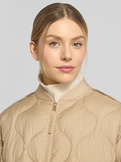 Frauenmodel trägt Steppjacke mit Stehkragen und Zweiwege-Reißverschluss Modell 'IMANE' von Beaumont Amsterdam, beige, Nahaufnahme Oberkörper, Relaxed-Fit, Damen, Rückenlänge 55 cm, Schulterbreite 44 cm, Brustweite 60 cm, Ärmellänge 61 cm.