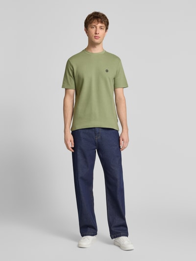 Männermodel trägt Herren T-Shirt mit Label-Detail Modell 'FILLIP' von Blend in Grün, Reine Baumwolle, Gerader-Schnitt, Rundhalsausschnitt, Rückenlänge bei Größe M 69 cm, Ganzkörperansicht von vorne.