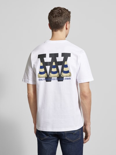 Męski model nosi T-Shirt mit rückseitigem Motiv- und Logo-Print od Wood Wood z czystej bawełny, krój regular fit, biały kolor, nadruk z tyłu, całkowity widok od tyłu