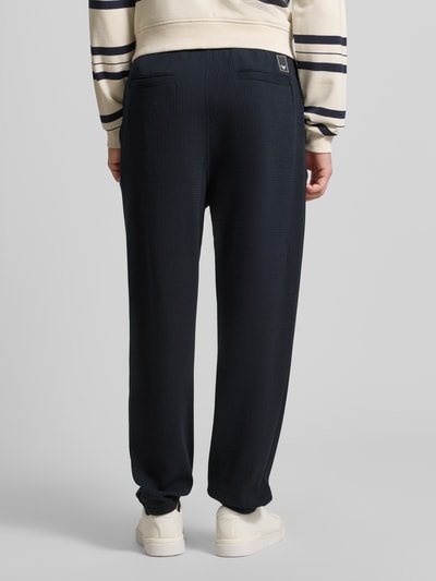 Männermodel trägt Hose mit Strukturmuster und Eingrifftaschen von Emporio Armani, Regular-Fit, Material-Mix mit Viskose-Anteil, dunkelblau, Gesäßtaschen, Bundweite 46 cm, Innenbeinlänge 73 cm, Ganzkörperansicht Rückansicht.