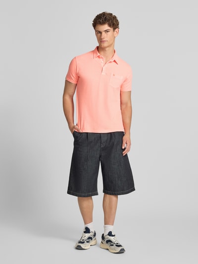 Männermodel trägt Slim Fit Poloshirt mit Brusttasche von Superdry aus Baumwoll-Leinen-Mix, Knopfleiste, Rückenlänge 67 cm, Ganzkörperansicht von vorne.