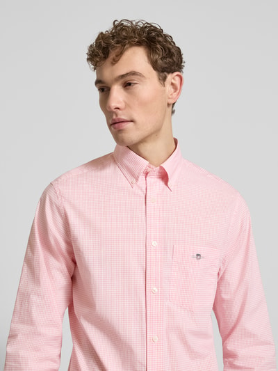 Mannelijk model draagt licht roze 'Slim Fit Freizeithemd mit Logo-Stitching' van Gant, pure katoen, button-down kraag, borstzak; close-up bovenlichaam.