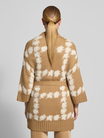 Frauenmodel trägt Cardigan mit Bindegürtel und 3/4-Arm von Marc Cain, beige-weiß gemustert, Material-Mix mit Alpaka, Ganzkörperansicht Rückansicht.