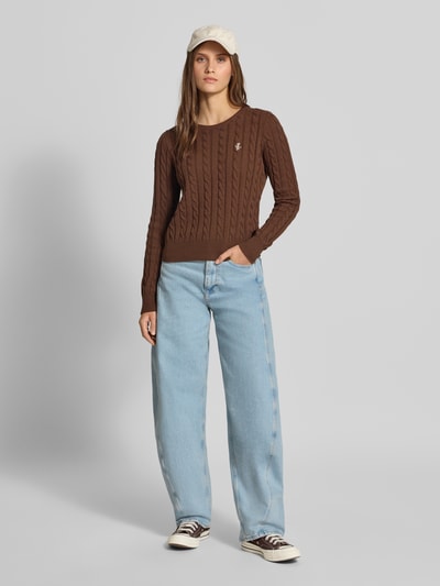 Vrouwenmodel draagt Slim Fit Pullover aus Baumwoll-Mix van REVIEW in bruin met tricotlook, ronde hals, ruglengte maat S 53 cm, mouwlengte 68 cm, gebreide textuur, lichte jeans, ganzebody van voren.