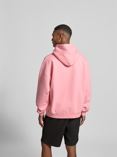Männermodel trägt Hoodie mit Statement-Stitching von Dsquared2 in Rosa, reine Baumwolle, Relaxed Fit, Rückansicht Ganzkörperansicht.