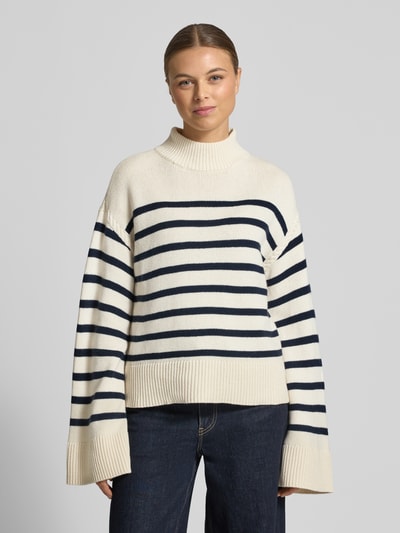 Frauenmodel trägt Regular Fit Pullover aus Woll-Mix Modell 'Sharad' von Lauren Ralph Lauren, cremefarben mit dunkelblauen Querstreifen, Stehkragen und breite Abschlüsse, Ganzkörperansicht von vorne.
