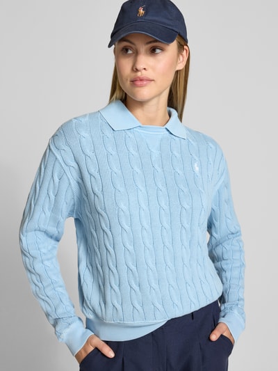 Frauenmodel trägt Regular Fit Pullover mit Polokragen von Polo Ralph Lauren in Hellblau mit Zopf-Strukturmuster aus Baumwolle, Nahaufnahme Oberkörper.