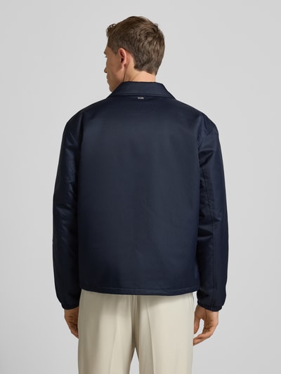 Männermodel trägt Regular Fit Blouson mit Logo-Muster Modell 'H-CRESTELL' von BOSS, dunkelblau, Allover-Muster, Ganzkörperansicht Rückansicht.