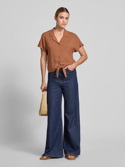 Frauenmodel trägt Regular Fit Bluse aus Viskose mit Knotendetail Modell 'RADIA' von Soyaconcept in Braun mit Reverskragen, Knopfleiste, Rückenlänge bei Größe S 55 cm, Ärmellänge 10 cm, Ganzkörperansicht von vorne.
