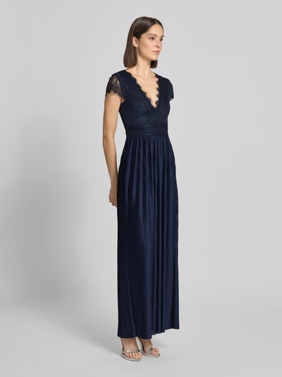 Frauenmodel trägt Abendkleid in Falten-Optik Modell 'Emelie' von GUIDO MARIA KRETSCHMER WOMAN aus navyblauem Satin, V-Ausschnitt, Spitzenbesatz und Maxilänge, taillierte Passform, Kurzarm, Ganzkörperansicht von vorne.