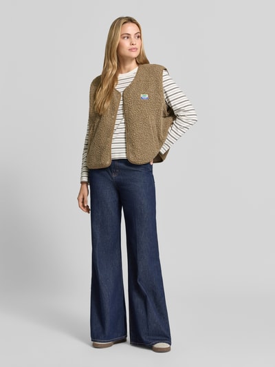 Frauenmodel trägt Regular Fit Weste aus Teddyfell Modell 'Hoktown' von American Vintage, beige, strukturierte Oberfläche, Ganzkörperansicht von vorne. Damen Weste aus Teddyfell mit Logo-Patch, Knopfleiste, Rückenlänge 57 cm, Schulterbreite 43 cm, Brustweite 63 cm, Kontext: Damenmode.