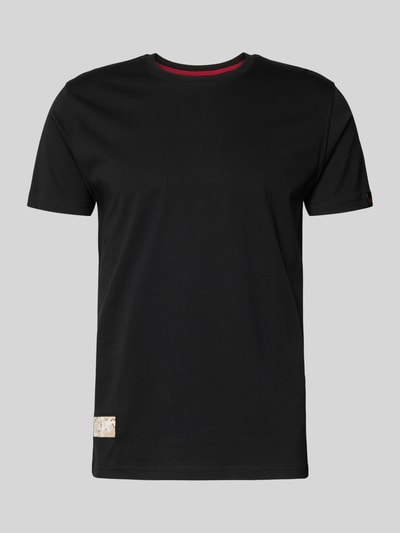 Produktfoto, schwarzes T-Shirt mit Label-Patch Modell 'Camo' von Alpha Industries aus gewachster Baumwolle, gerader Schnitt, rote Hals-Innenseite.