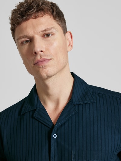 Männermodel trägt Regular Fit Freizeithemd aus reiner Baumwolle Modell 'RAYER_M' von BOSS Orange, dunkelblau gestreift, Nahaufnahme Oberkörper.