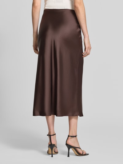 Frauenmodel trägt Midirock aus Satin von Rich & Royal, braun glänzend, gerader Schnitt, elastischer Bund, Ganzkörperansicht Rückansicht.