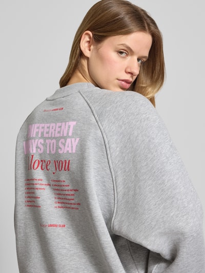 Frauenmodel trägt Sweatshirt mit Label-Print Modell 'Loretta' von LeGer by Lena Gercke im Loose Fit aus grauem Baumwoll-Mix, Ganzkörperansicht Rückansicht.