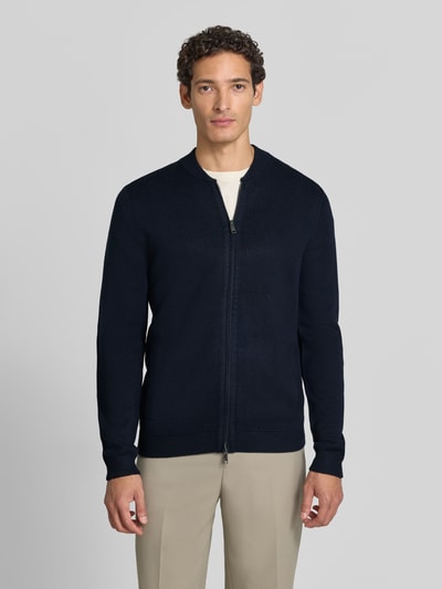 Männermodel trägt Slim Fit Strickjacke aus Baumwoll-Mix mit Stehkragen von Christian Berg Men in Dunkelblau, Zweiwege-Reißverschluss, gerippte Abschlüsse, Ganzkörperansicht von vorne.