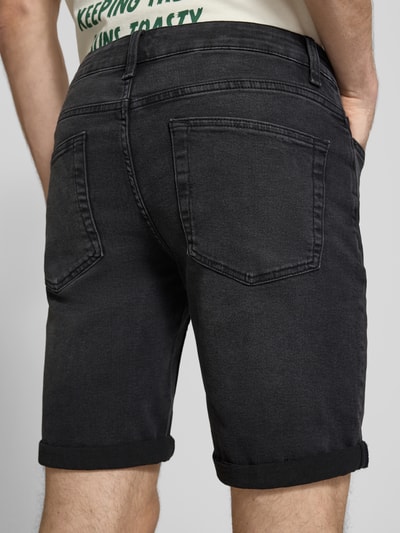 Männermodel trägt Regular Fit Jeansshorts aus bawełny z dodatkiem wiskozy Modell 'SPY' von Only & Sons, splot twill, czarne, 5 kieszeni, naszywka z logo, szlufki na pasek, zapięcie na guzik i ukryty zamek błyskawiczny, Ganzkörperansicht Rückansicht.
