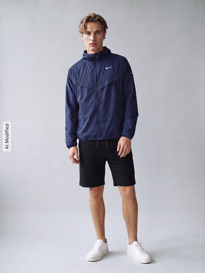 Männermodel trägt Regular Fit Trainingsjacke aus reiner Baumwolle Modell 'STRIDE' von Nike in Dunkelblau, Herren Trainingsjacke, Ganzkörperansicht von vorne, KI-modifiziertes Bild.