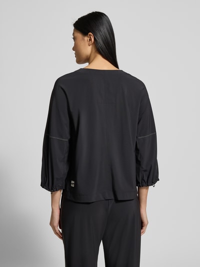 Vrouwenmodel draagt Hoodie met Labelprint van Marc Cain in zwart, materiaalmix met stretch, los model, capuchon, ribboorden, ruglengte 54 cm, mouwlengte 43 cm. Ganzkörperansicht Rückansicht.