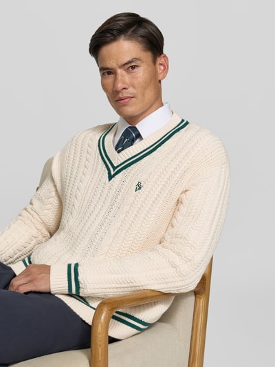 Männermodel trägt Strickpullover mit Zopfmuster von REVIEW in Creme mit Kontraststreifen, V-Ausschnitt, Nahaufnahme Oberkörper.