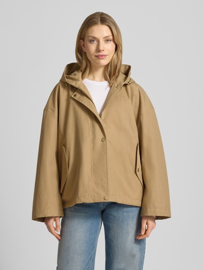 Frauenmodel trägt Jacke mit Kapuze und versiegelten Nähten Modell 'ELLE' von G-LAB aus Lyocell-Mix mit Leinen-Anteil in Beige, Gerader-Schnitt, Wasserdicht, Winddicht, Atmungsaktiv, Reißverschluss und Druckknopfverschluss, seitliche Pattentaschen, Ganzkörperansicht von vorne.