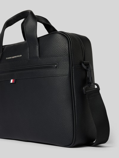 Produktfoto, Laptoptasche in Leder-Optik von Tommy Hilfiger, schwarze Farbe, strukturierte Oberfläche, kurze Henkel, abnehmbarer Schulterriemen, zentraler Brand-Schriftzug und Logo-Motiv, Außentasche mit Reißverschluss, Hauptfach mit Laptopfach und Innentaschen, Maße Breite 40 cm, Länge 35 cm, Tiefe 10 cm, Länge Schulterriemen 95 cm.