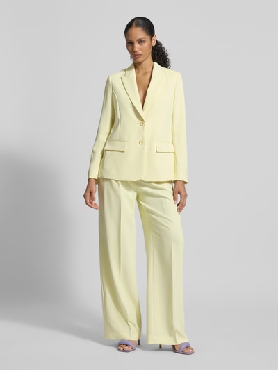 Modelka kobieca ma na sobie Regular Fit Blazer mit Reverskragen od Marc Cain z elastycznej mieszanki materiałów, jasny żółty, klapy z patkami, zapięcie na dwa guziki, długość tyłu w rozmiarze 36: 66 cm, szerokość w rozmiarze 36: 48 cm, długość rękawa w rozmiarze 36: 62 cm, widok całej sylwetki od frontu