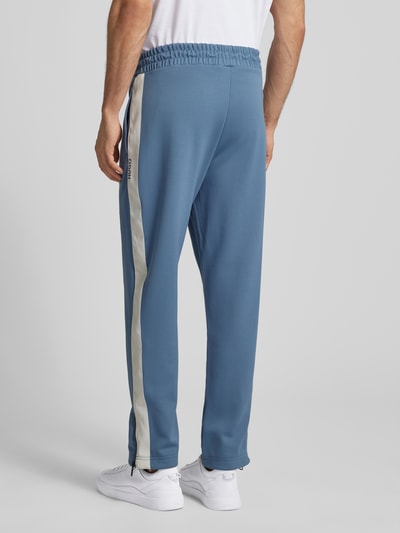 Männermodel trägt Relaxed Fit Jogginghose mit Galonstreifen Modell 'DOLOS' von HUGO in Optik: Unifarben, Sweat, Ganzkörperansicht Rückansicht