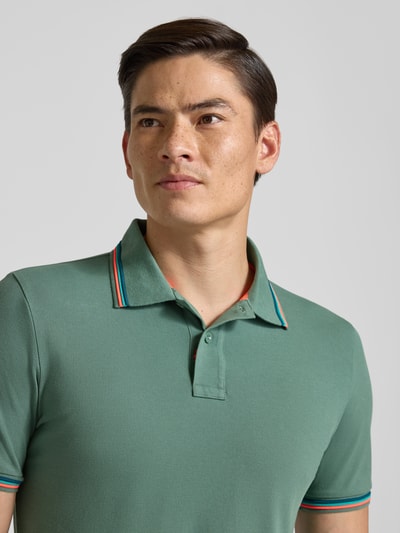 Männermodel trägt Slim Fit Poloshirt mit Kontraststreifen Modell 'Brice' von Sundek aus Baumwoll-Elasthan-Mix, Nahaufnahme Oberkörper.