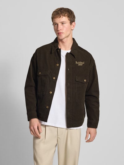 Männermodel trägt Regular Fit Hemdjacke aus reiner Baumwolle Modell 'Pitstop' von PROHIBITED in Braun mit Cord, Umlegekragen, Brusttaschen, Label-Applikation in metallic, durchgehende Knopfleiste, Ganzkörperansicht von vorne.