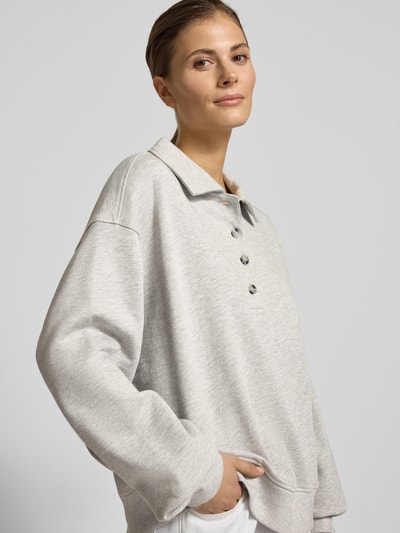 Vrouwenmodel draagt Sweatshirt met Polokragen en Knopfleiste van Gina Tricot, lichtgrijs, oversized, Regular Fit, detailopname bovenlichaam.