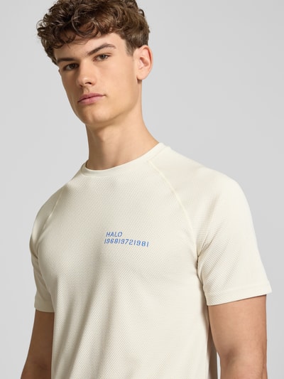 Männermodel trägt cremefarbenes Herren T-Shirt mit Label-Print Modell 'SORONA' von HALO, Regular Fit, Rundhalsausschnitt, Nahaufnahme Oberkörper.
