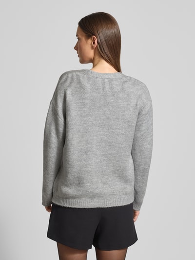 Frauenmodel trägt Strickjacke mit Knopfleiste von More & More in Hellgrau, lockerer Schnitt, V-Ausschnitt, gerippte Abschlüsse, Ganzkörperansicht Rückansicht