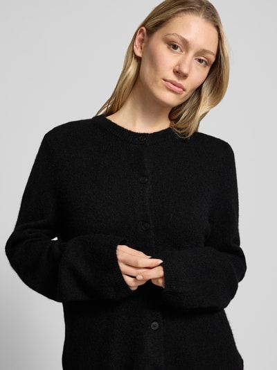 Kobiece model prezentuje kardigan rozpinany Regular Fit Strickjacke aus Woll-Mix mit Alpaka-Anteil Modell 'LULU NEW' od Selected Femme, efekt: jednolity kolor, krój regular fit, listwa guzikowa, dekolt okrągły, długi rękaw, zakończenia rękawów i wykończenie: prążkowane, wykończenie materiału: dzianina, materiał: mieszanka wełny; Nahaufnahme górnej części ciała.