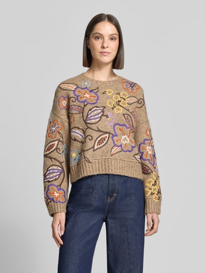 Vrouwenmodel draagt Regular Fit Pullover met wol in tricotlook van Oui, elastische materiaalmix, all-over bloemenmotief, ronde hals, ruglengte 51 cm bij maat 36, mouwlengte 58 cm, vooraanzicht volledige lichaamsopname.