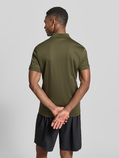 Männermodel trägt olivgrünes Regular Fit Poloshirt aus reiner Baumwolle Modell 'PS Spirit 70 Plk' von BOSS Green X PORSCHE, Ganzkörperansicht Rückansicht.