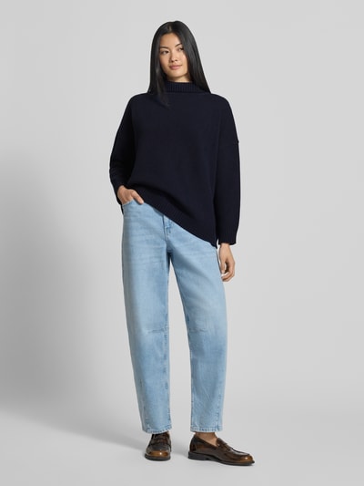 Modelka nosi granatowy sweter Loose Fit Pullover aus reiner Wolle model 'BORGIA' od Weekend Max Mara, jasnoniebieskie jeansy, brązowe buty, jednolity kolor, miękka faktura, całopostaciowe ujęcie z przodu.