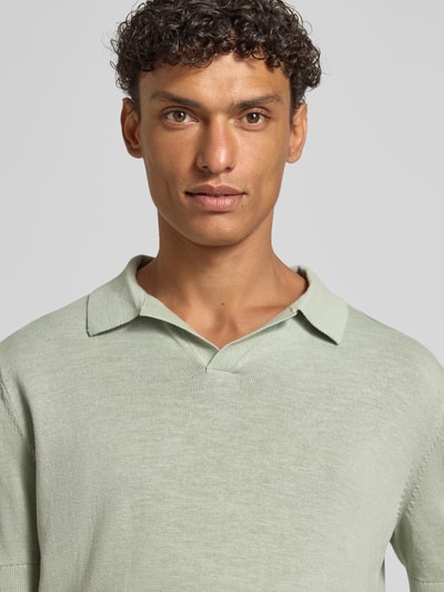 Männermodel trägt Regular Fit Poloshirt aus Baumwoll-Leinen-Mix Modell 'MATTIS' von SELECTED HOMME in Hellgrün, Feinstrickstruktur, unifarben, Nahaufnahme Oberkörper.