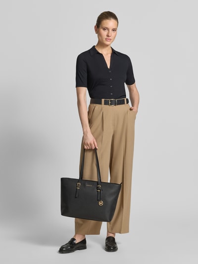 Kobiece model prezentuje torebkę Handtasche aus echtem Leder mit Logo-Detail Modell 'Qiunn' von MICHAEL Michael Kors, czarny kolor, złote detale, główna przegroda z zamkiem błyskawicznym, smukłe paski na ramię, detal z logo, Szerokość w rozmiarze 1: 45 cm, długość w rozmiarze 1: 28 cm, głębokość w rozmiarze 1: 15 cm, długość paska na ramię w rozmiarze 1: 69 cm, widok całej sylwetki z przodu.