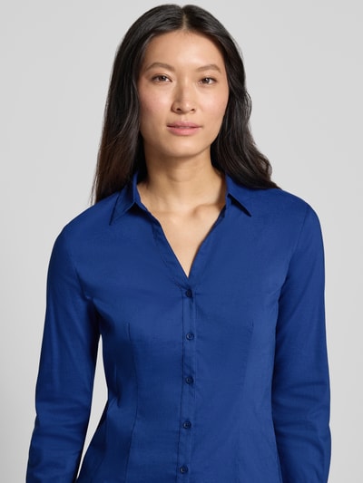 Frauenmodel trägt Hemdbluse aus Baumwoll-Mix von MORE & MORE in kräftigem Blau, taillierte Passform, Nahaufnahme Oberkörper. Rückenlänge 61 cm, Ärmellänge 59 cm, Hemdblusenkragen, durchgehende Knopfleiste, langärmeliges Design.