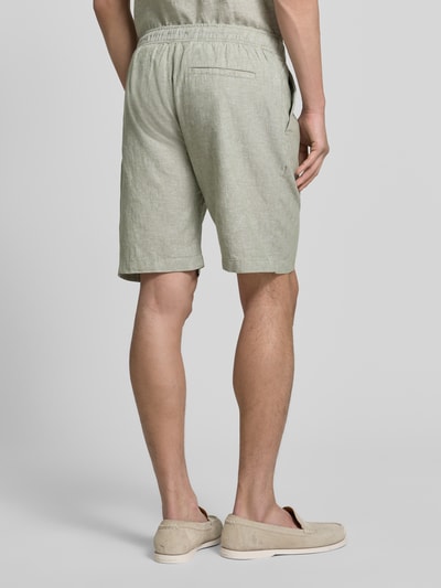 Männermodel trägt Shorts aus Leinen-Baumwoll-Mix mit elastischem Bund von MCNEAL, Regular-Fit, dezente grüne Farbe, Ganzkörperansicht Rückansicht, Kontext: Herren Shorts, Tunnelzug, Bundweite bei Größe M 44 cm, Innenbeinlänge bei Größe M 23 cm.