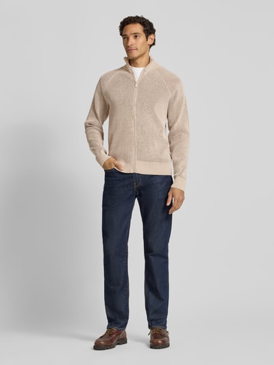 Männermodel trägt Regular Fit Strickjacke mit Stehkragen von Jake*s Studio Men, beige, dezente Struktur, kombiniert mit Jeans, Ganzkörperansicht von vorne.