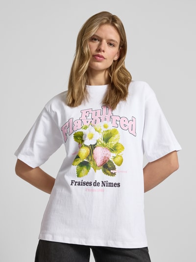 Frauenmodel trägt Loose Fit T-Shirt mit Motiv-Print Modell 'MILLOW' von JJXX aus weißer Baumwolle, Rundhalsausschnitt, Ganzkörperansicht von vorne.
