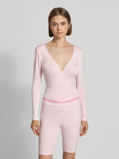 Frauenmodel trägt Cardigan in Wickel-Optik Modell 'Luca' von OH APRIL in zartem Rosa, glatte Textur, Slim Fit, V-Ausschnitt, Nahaufnahme Oberkörper. Modal-Elasthan-Mix, Rückenlänge bei Größe S 46 cm.