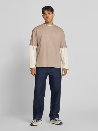 Männermodel trägt Oversized T-Shirt mit Backprint und Rundhalsausschnitt von PEGADOR aus reiner Baumwolle in Beige, Ganzkörperansicht von vorne.