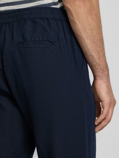 Männermodel trägt Straight Fit Hose aus linnenmix van Filippa K, mix van katoen en linnen, persplooien, achterzak, elastische band, detailaufnahme achterkant.