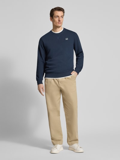 Męski model nosi Regular Fit Sweatshirt aus Baumwoll-Mix von s.Oliver RED LABEL, jednokolorowa, wyhaftowane logo, okrągły dekolt, prążkowane wykończenia, dzianina dresowa, mieszanka bawełny, Ganzkörperansicht von vorne.